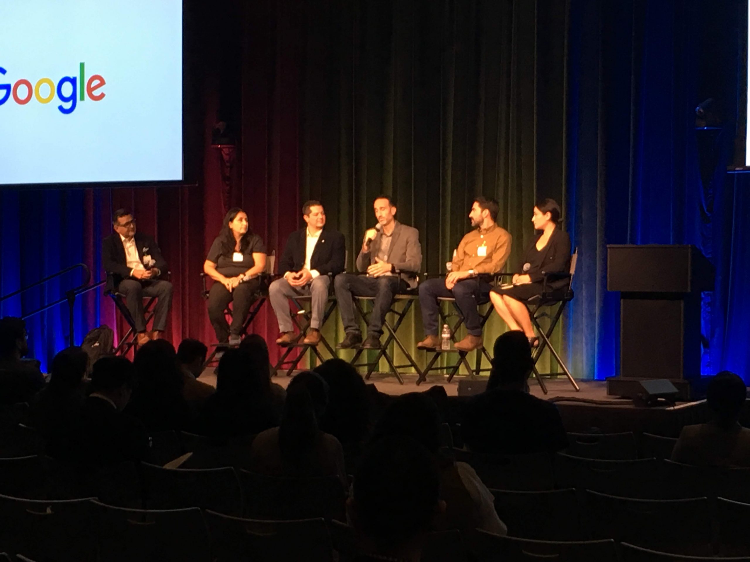 Panelists speaking on the symposium stage